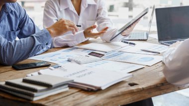 Three business people meeting at wooden desk, analysis and calculate accounting finance data, stats.