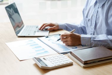 Masaya konan faturaların giderlerini hesaplamak için hesap makinesi kullanan bir iş adamının ellerini kapat. vergi kavramı.