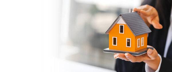Real estate concept, businesswoman holding a house model, Property insurance and security concept.