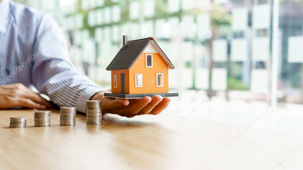 Hand choosing row of coin money house Planning to buy property or new home.