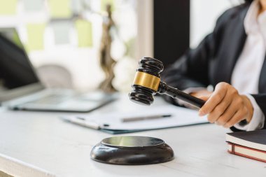 Kadın yargıç, mahkeme salonunda tokmağı tutmak için elini tutuyor..