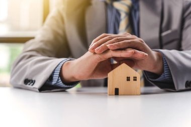 İş adamı, ev modeli, emlak sigortası konsepti. İpotek ve vergi ödemeleri. 