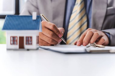 İş adamı, ev modeli, emlak sigortası konsepti. İpotek ve vergi ödemeleri. 