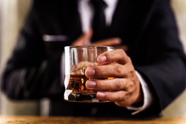 Yöneticinin yürütme ayrıcalığı kavramını göstermek için tahta masada viski tutmasına yakın çekim.