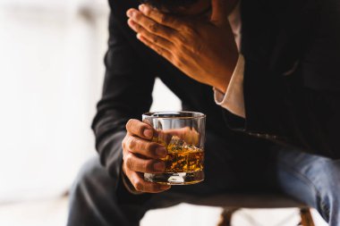 Alkolizm, depresyondaki Asyalı genç adam alkollü içecek içerken masada uyur, geceleri bir bardak viskiyi tek başına tutar. Alkol bağımlılığının tedavisi, taciz sorunu alkolizm kavramı