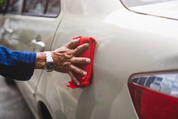 Man\'s hand cleaning car & drying vehicle with microfiber cloth. Hand wipe down paint surface of shiny blue sedan after polishing and ceramic coating. Car detailing, maintenance, and car wash concept.