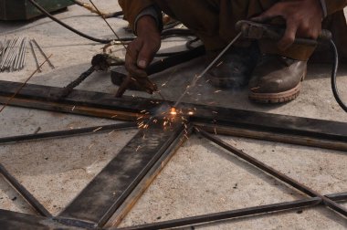 Çelik kaynaklama, kaynakçı çalışıyor. Çitin metal çerçevesinin kaynaklanması, yakın plan..