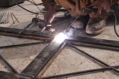 Çelik kaynaklama, kaynakçı çalışıyor. Çitin metal çerçevesinin kaynaklanması, yakın plan..