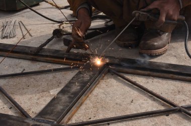 Çelik kaynaklama, kaynakçı çalışıyor. Çitin metal çerçevesinin kaynaklanması, yakın plan..