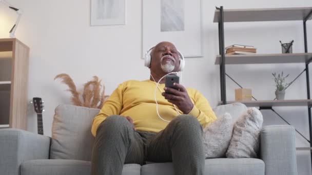 Насолоджуючись музикою щасливий старший чоловік додому дозвілля — стокове відео