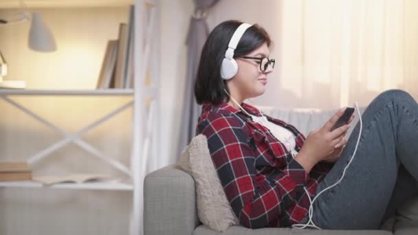 Мобільна музика пісня прослуховування жінки навушники диван — стокове відео