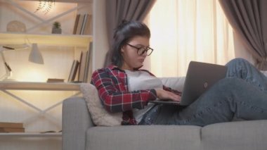 Serbest çalışan uzaktan kumandalı kadın dizüstü bilgisayar kanepe evi