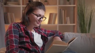 Akşam kitap okuyarak evde dinlenen boş bir kadın.