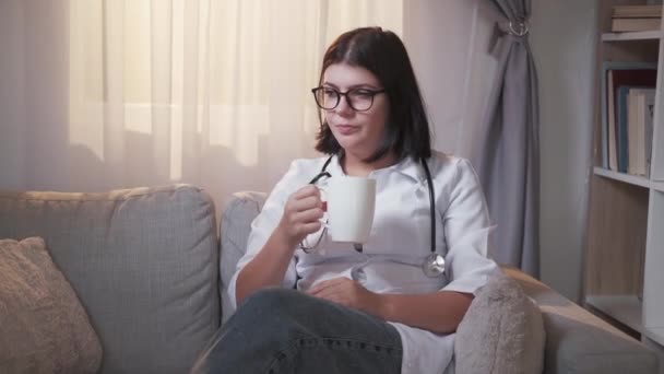 Orvos iszik kávé szünet nő kanapé — Stock videók