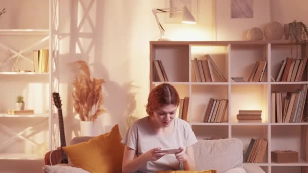 Мобільний ігровий телефон розваги щаслива жінка вдома — стокове відео