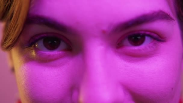 Kadın gözleri neon makyajı renkli pembe ışık — Stok video