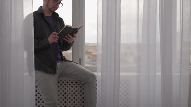 Rahatlatıcı kitap okumak boş zamanların adamı rahat ev penceresi — Stok video