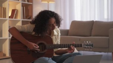Gitar öğrenen müzik sınıfındaki kadın evde pratik yapıyor.