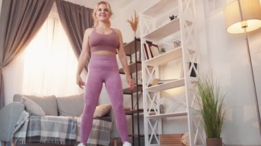 Spor salonundaki kadın çömelmiş spor yapıyor.