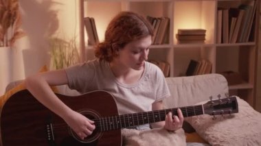Müzik alıştırması yapan gitar çalan kadın akorlarını evde yapıyor.