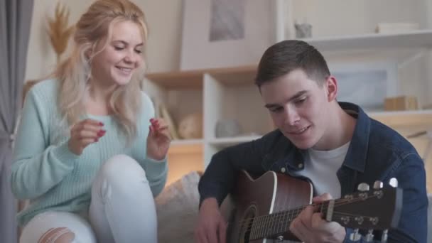 Музичне дозвілля пара охолоджує чоловіка гітара жінка вдома — стокове відео