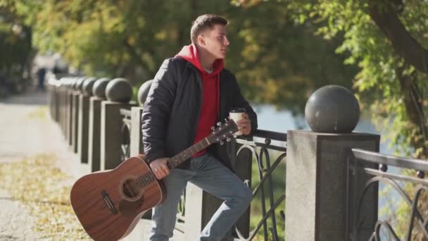 Venkovní chůze káva přestávka muž kytara park ulice — Stock video