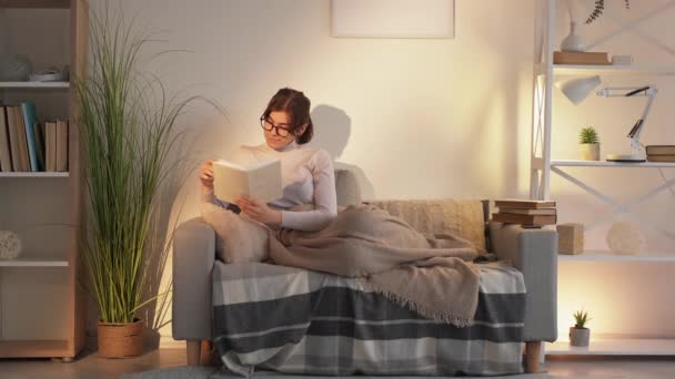 Casa leitura livro de lazer relaxante mulher sofá — Vídeo de Stock
