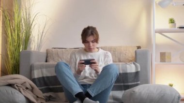 Telefon oyunu aleti bağımlısı kadın evde oynuyor.