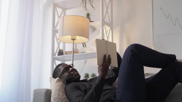 Rezervovat volný čas čtení hobby muž relaxační pohovka doma — Stock video
