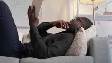 Edebiyat araştırma kitabı aşığı kanepede yatıyor.