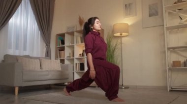 Yogi kadın, evde hobi olarak eğitilmiş savaşçı pozu veriyor.