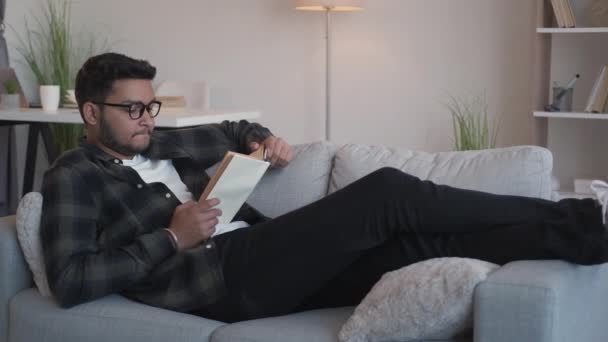 Lectura libro relajarse conocimiento ocio hombre sofá — Vídeos de Stock