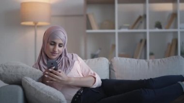 Cep telefonu, kadın kanepe evinde geziniyor.