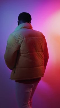 Tuhaf adam. İyimser yaşam tarzı. Serbest stil dansı. Gece hayatı eğlencesi. Neşeli, dost canlısı bir adam parlak neon ışıklarıyla barış jesti yapıyor..