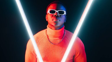 Siber punk modeli. Tekno moda. Sentetik dalga arka planı. Kendine güveni olan, neon ışıklı havalı adam LED lamba, siyah pankartta tek başına parlıyor..