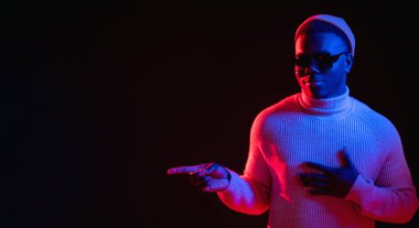 Tavsiye edilen adam. Neon ışığı reklamı. Terfi afişi. İndirim teklifi. Havalı, neşeli, boş uzay karanlık arka planını gösteren adam..