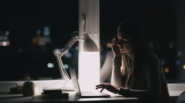 Sıkıcı kadın. İnternet taraması. Geç saatlere kadar. Canı sıkkın kadın çalışan dizüstü bilgisayar gece penceresinde iş yerinde internette geziniyor..