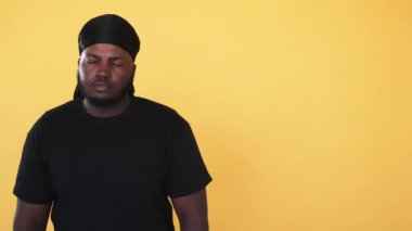 Ciddi bir afro adam. Siyahların hayatı önemlidir. Sosyal çeşitlilik. Farklı bir kültür. Kendine güveni tam bir Afrikalı, turuncu fotokopi arkaplanında izole edilmiş..