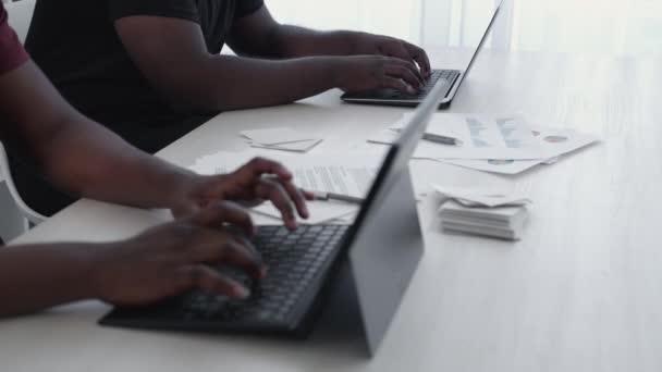 笔记本电脑的研究 业务分析 项目管理 在写字台的工作空间 黑人男子在笔记本上边打字边核对统计数字的情况 — 图库视频影像