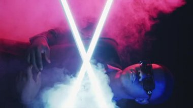 Şehirli bir adam. Gece hiphop 'u. Gece kulübü dansı. Renkli neon. Havalı stil sahibi genç bir müzisyen canlı yaratıcı duman efektiyle şarkı söylüyor..