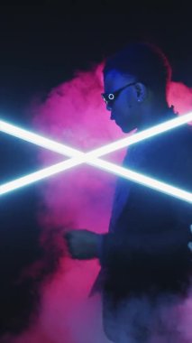 Dans eden adam. Neon partisi. Gece hayatı. Cuma eğlencesi. Mutlu kaygısız havalı adam gece kulübünde eğleniyor parlak mavi ışık dikey.