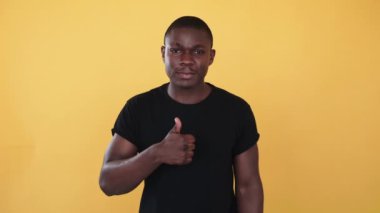 Onaylama jesti. Katılıyorum. Irksal hoşgörü. Harika bir fikir. Neşeli gülümseyen Afrikalı etnik adam turuncu arka planda izole edilmiş başarı sembolü gösteriyor.