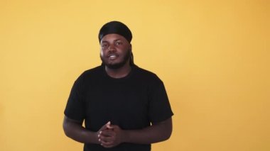 Siyahi adam konuşuyor. Duyuru reklamı. Blog etkileyicisi. Turuncu arka planda izole edilmiş bir hikaye anlatan karışık ırk Afro hoparlörü..