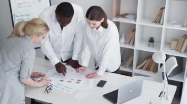 Takım çalışması toplantısı. İş brifingi. Proje stratejisi. Ofis konferansındaki çalışma masasında istatistik planlama grafiklerini tartışan kendine güvenen çeşitli meslektaşlar.