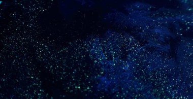 Parlak boya sıvısı. Volkan tozu. Koyu mavi sıvı akış arkaplan görüntüsünde odaksız altın pullu parıltı RED Sinema Kamerasında.