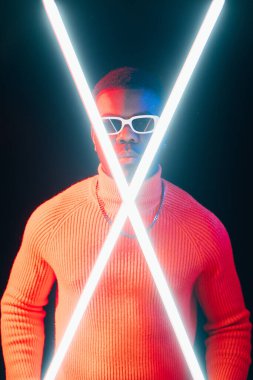 Erkek gücü. Neon ışığı insanları. Siberpunk bilim kurgu. Kendine güvenen ciddi bir erkek gece portresi, parlak LED lambaları, karanlık stüdyo arka planında..