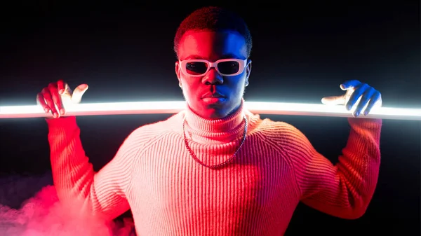 Neon light banner. Night life. High fashion. Stylish retrowave attractive man in sunglasses bright red glow LED lamp isolated on dark background.