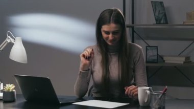 Kadın yazar. Sınav hazırlığı. Uzaktan eğitim. Akşamları evde ders çalışan mutlu ve ilham verici kız öğrenci laptopun çalışma yerinde ödev yazıyor..