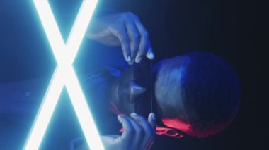 Neon hipster. Şık bir adam. Göz giyimi modası. Gülümseyen mutlu adam, gece dikey olarak kırmızı ve parlak güneş gözlüğü takıyor..