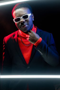 Çekici bir adam. Başarı güveni. Erkeksi moda. Gece stüdyosunun arka planında şık takım elbiseli yakışıklı, neon ışıklı adam..